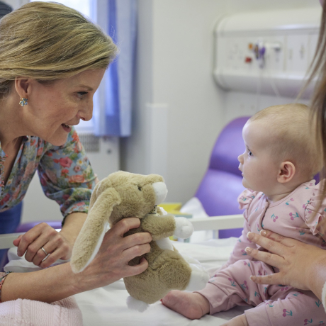 Duchess of Edinburgh interacting with a baby in the ward.
