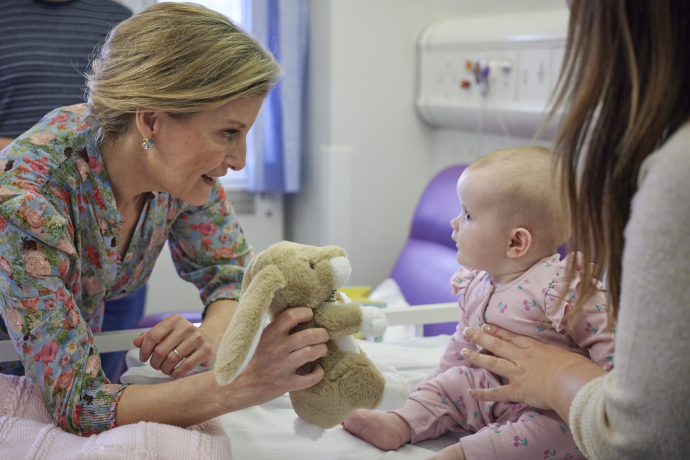 Duchess of Edinburgh interacting with a baby in the ward.