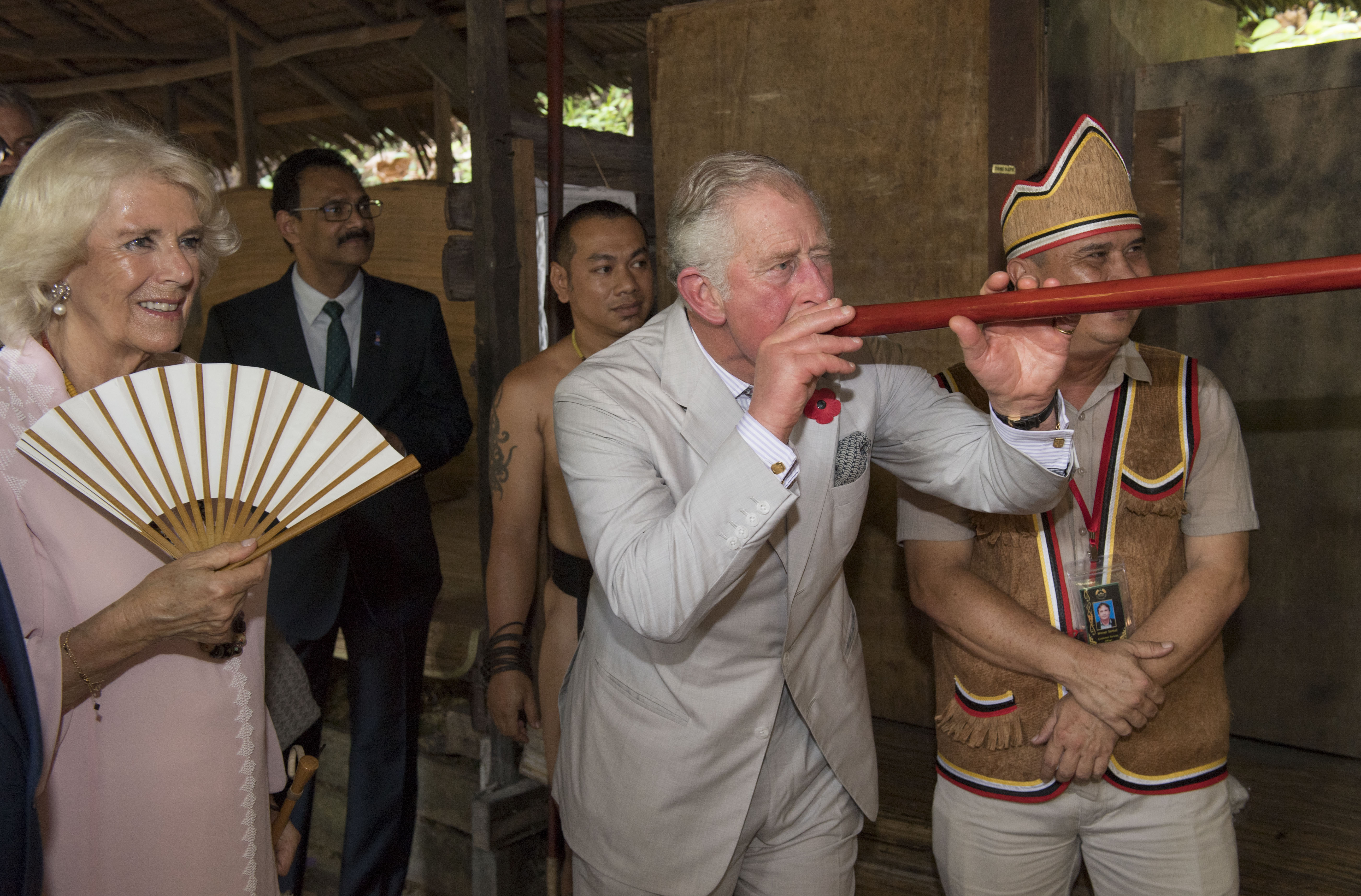 The Duchess of Cornwall watches as the Prince of Wales tries out a traditional blowgun during a visit to Sarawak Cultural Village