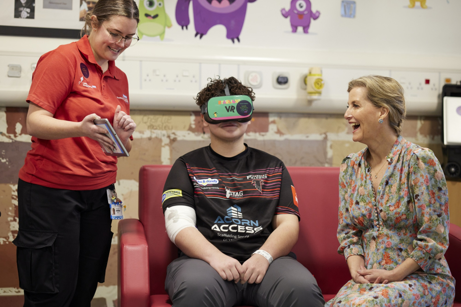 The Duchess of Edinburgh meets male patient and VR play specialist demonstrating Virtual Reality Distraction Therapy.