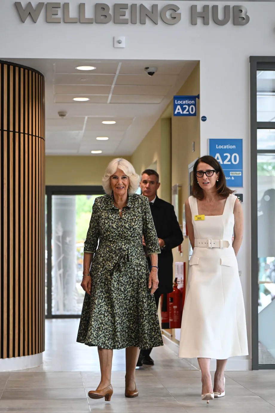 The Queen walks underneath a sign for the Wellbeing Hub