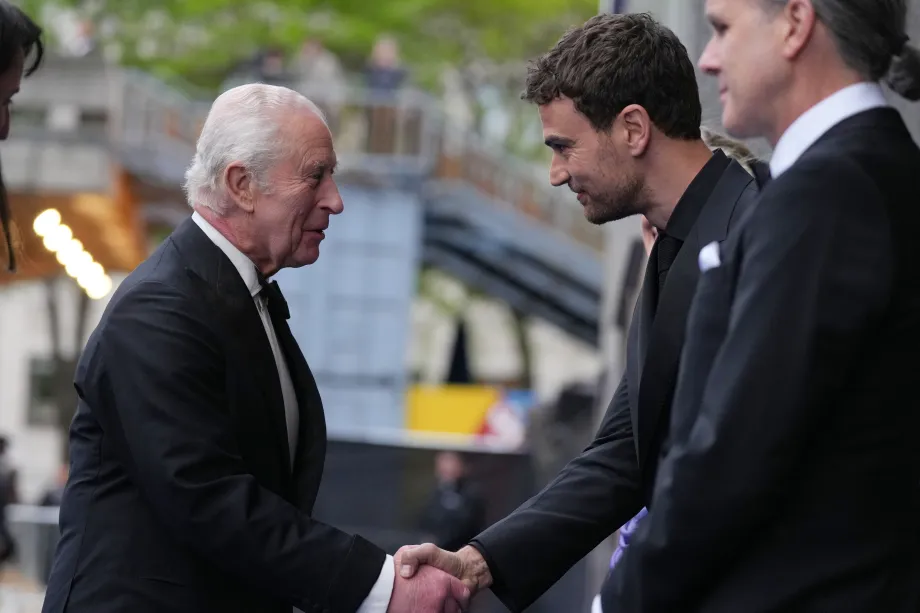 The King shakes hands with actor Theo James at the premiere of 'Ocean with David Attenborough