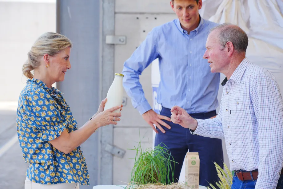 The Duchess of Edinburgh holds a bottle of milk at Trinity Farm